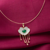 Gold necklace with a cloud-shaped pendant featuring a green gemstone on a red fabric background