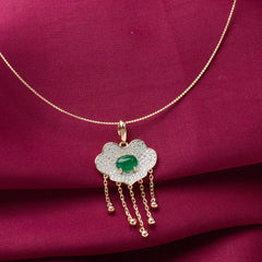 Gold necklace with a cloud-shaped pendant featuring a green gemstone on a red fabric background