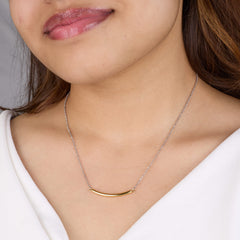 Close-up of a person wearing a gold necklace with a plain background