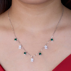 Necklace with green and clear square stones on a person wearing a red top.