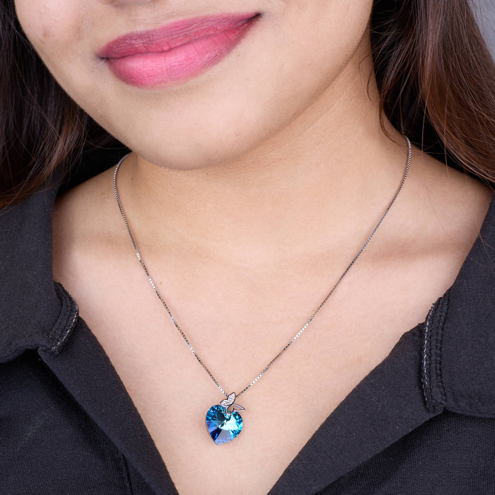 925 silver Close-up of a person wearing a necklace with a blue heart-shaped pendant.