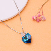 925 silver Necklace with a blue heart-shaped pendant on an orange surface with pink flowers.