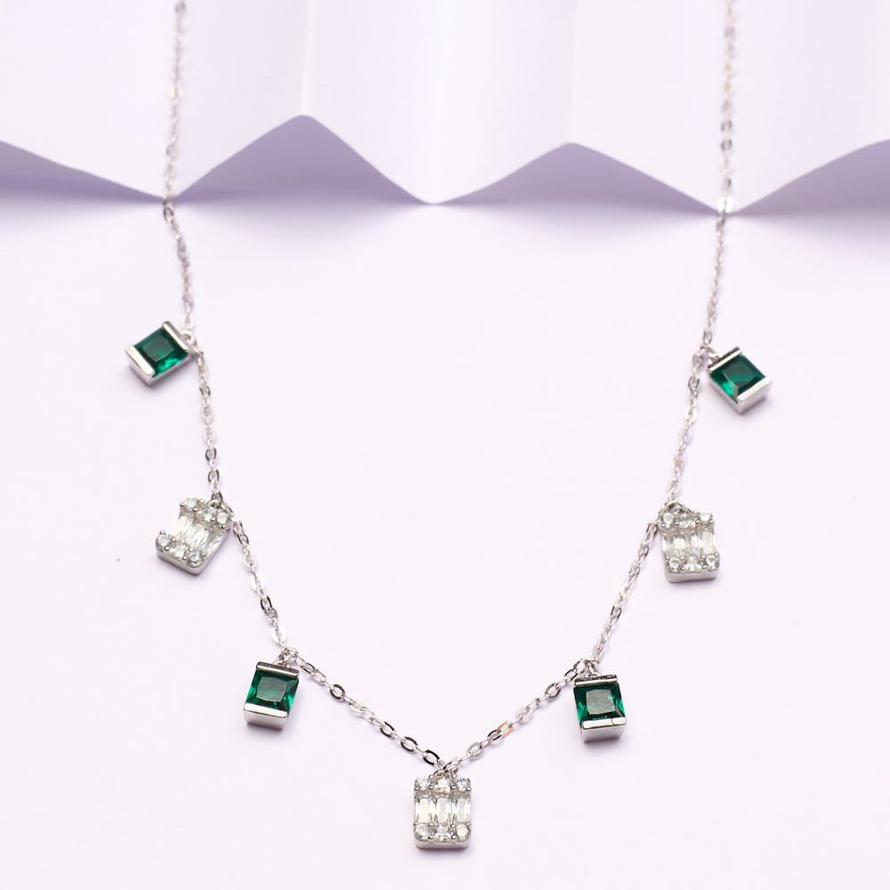 Silver necklace with green gemstones on a white background