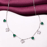 925 silver Necklace with heart-shaped emerald and diamond pendants on a white surface with a purple fabric background