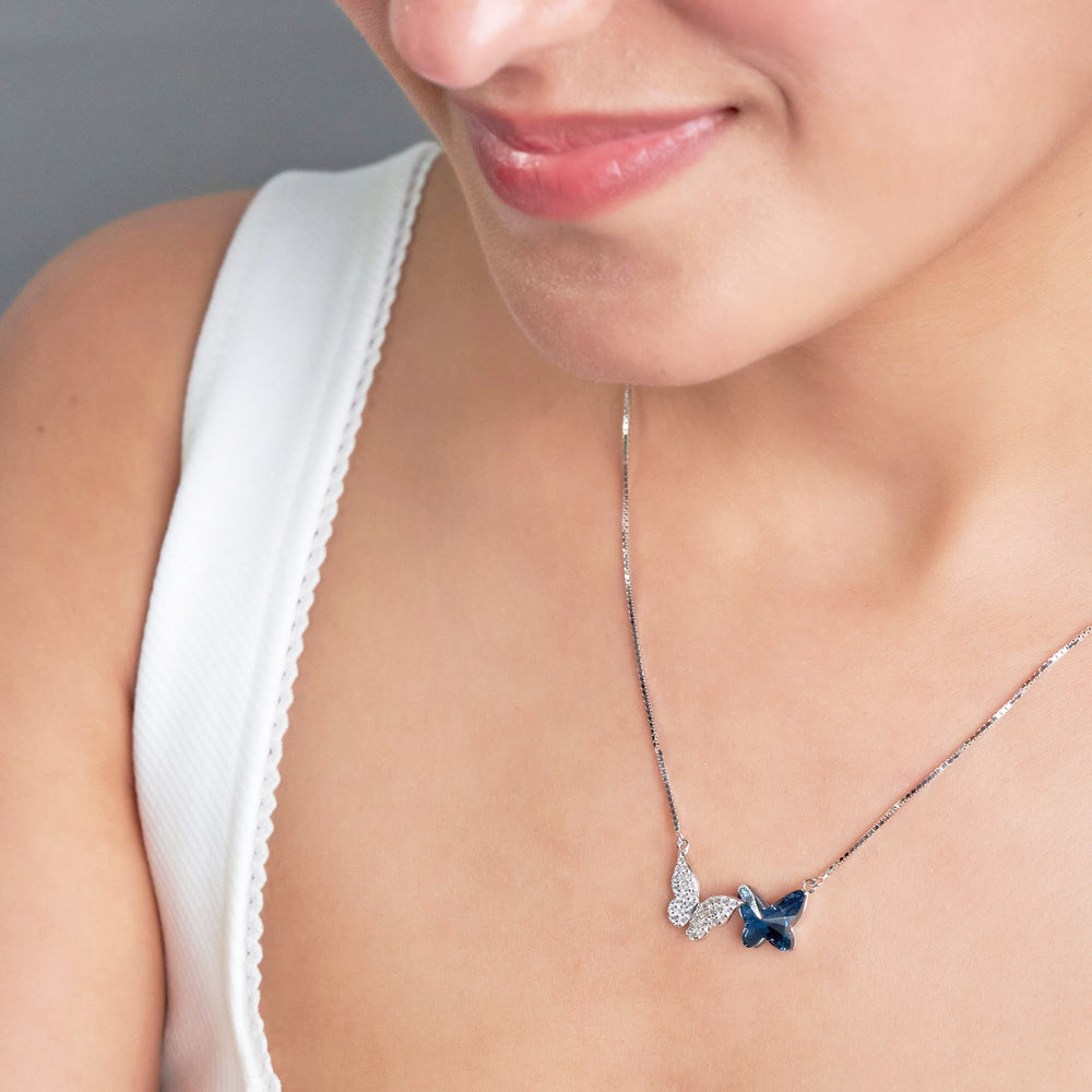 Butterfly necklace with a blue gemstone worn by a person