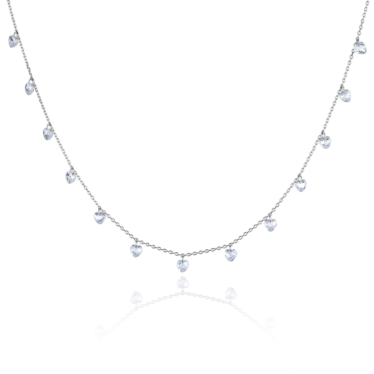 A delicate silver-toned necklace featuring a series of small, dangling heart-shaped clear gemstones along a fine chain, presented on a clean white background with a soft reflection below.