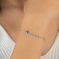 Silver bracelet with a blue eye charm on a person's wrist