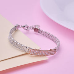 Silver bracelet with rose gold accents on a pink surface