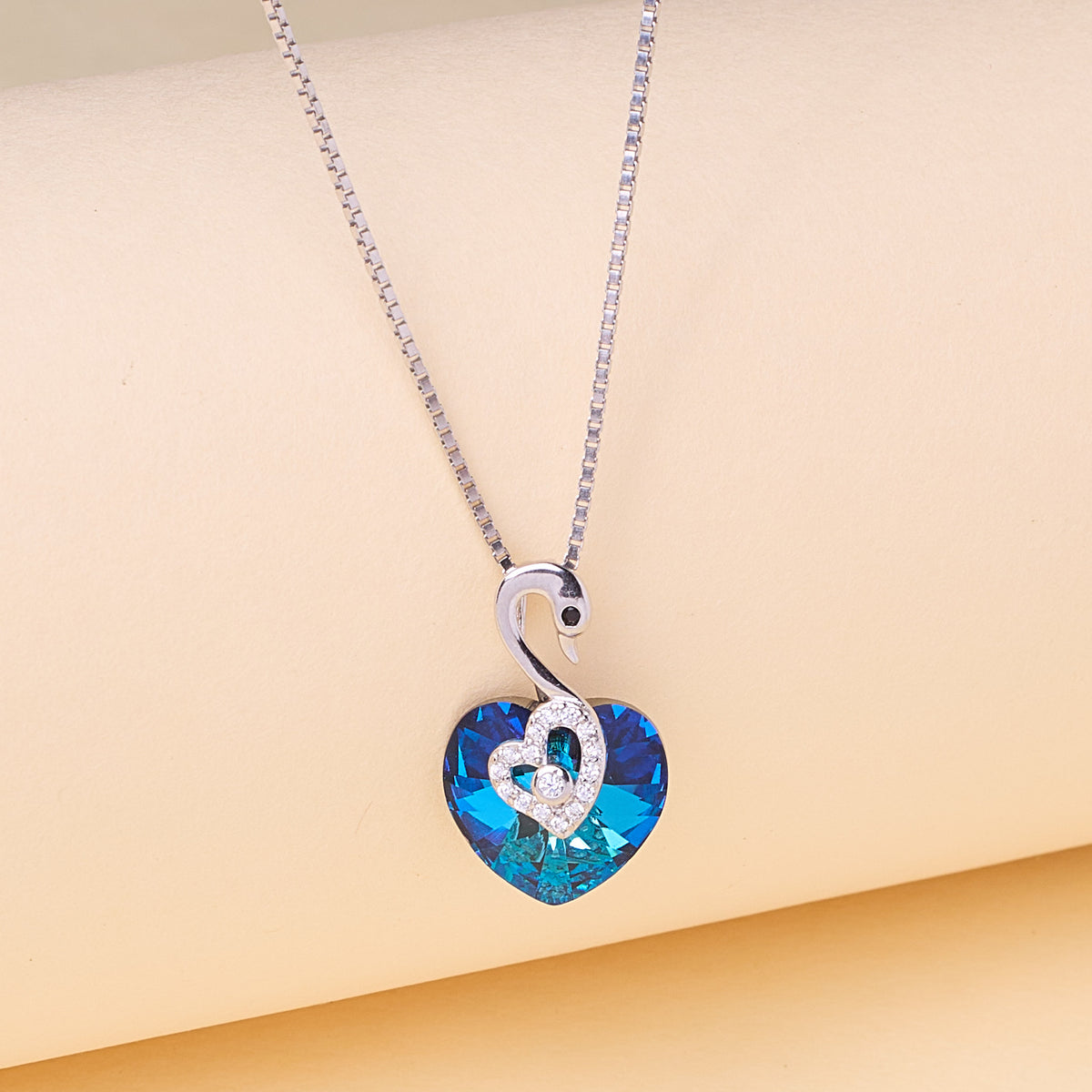 Necklace with a blue heart-shaped pendant on a beige background