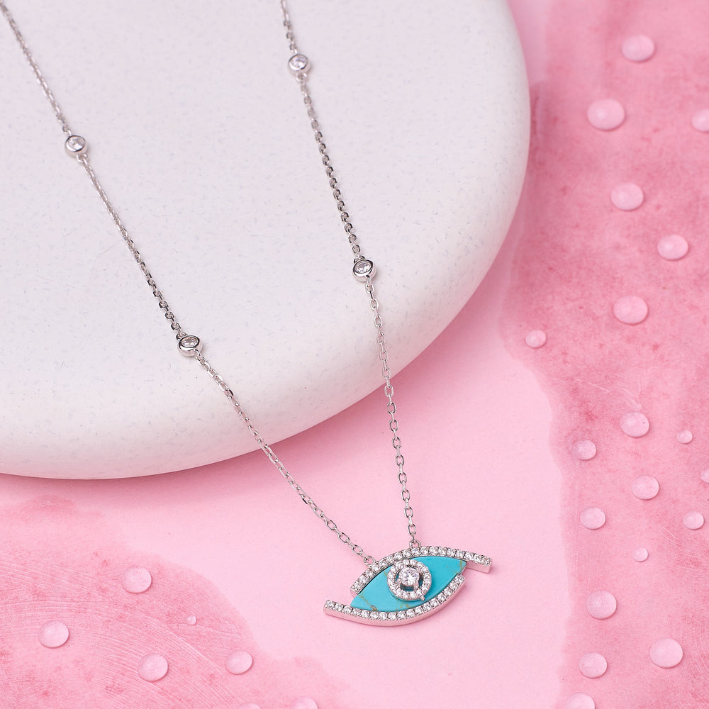 Necklace with a blue eye pendant on a pink background