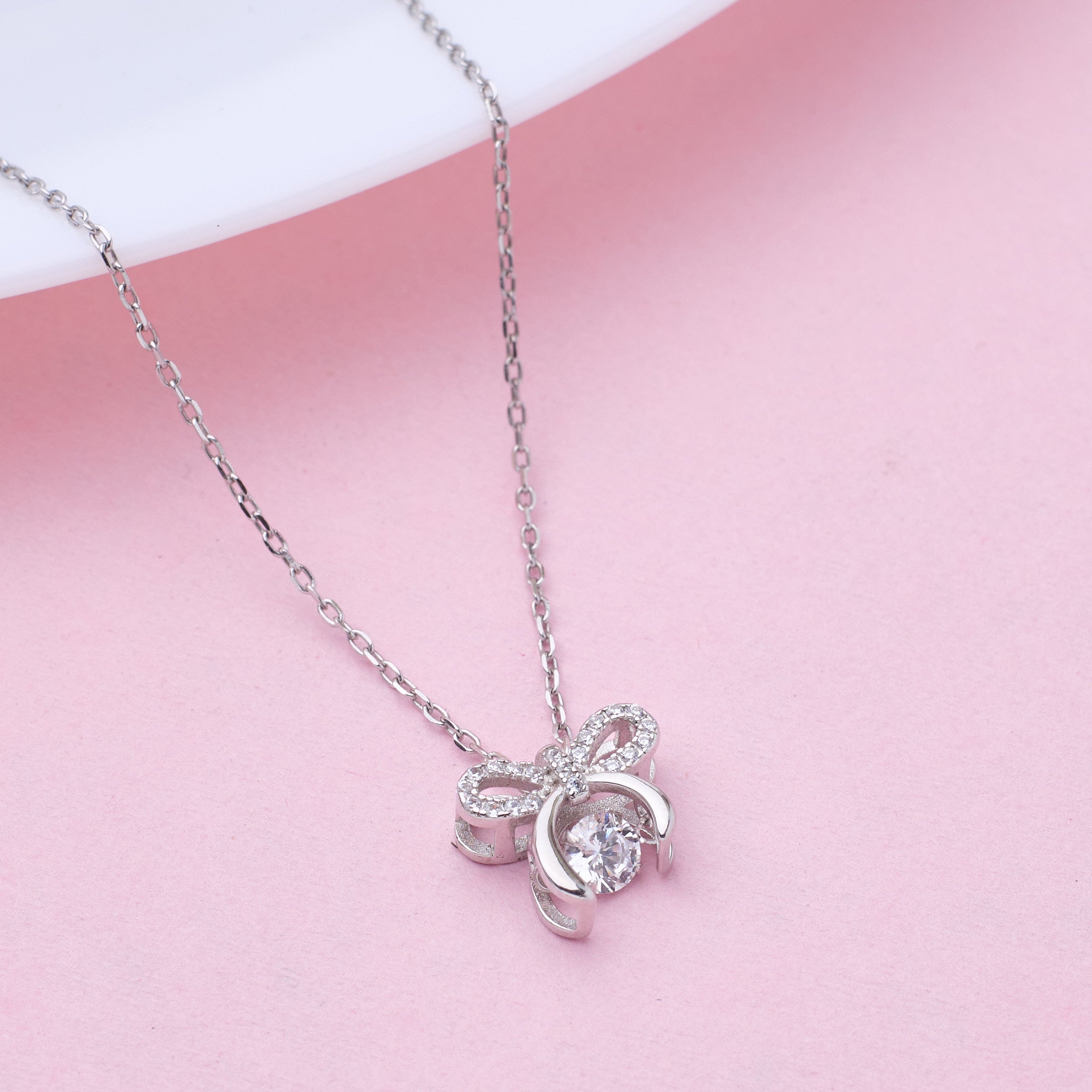 Pure 925 Silver pookie bow pendant necklace on a pink background