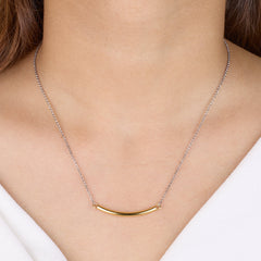 Gold necklace on a person's neck with a plain background