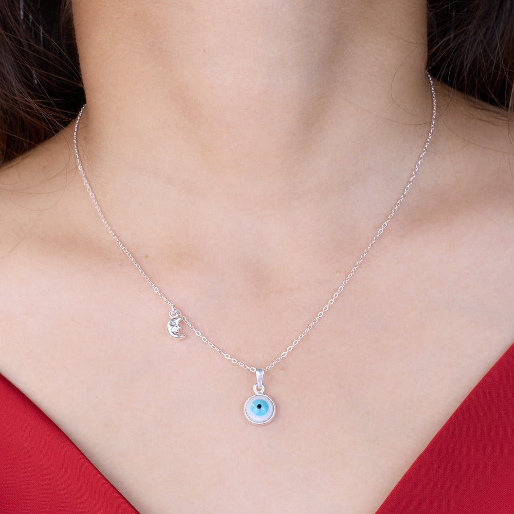 Necklace with a blue evil eye pendant worn by a person in a red top.