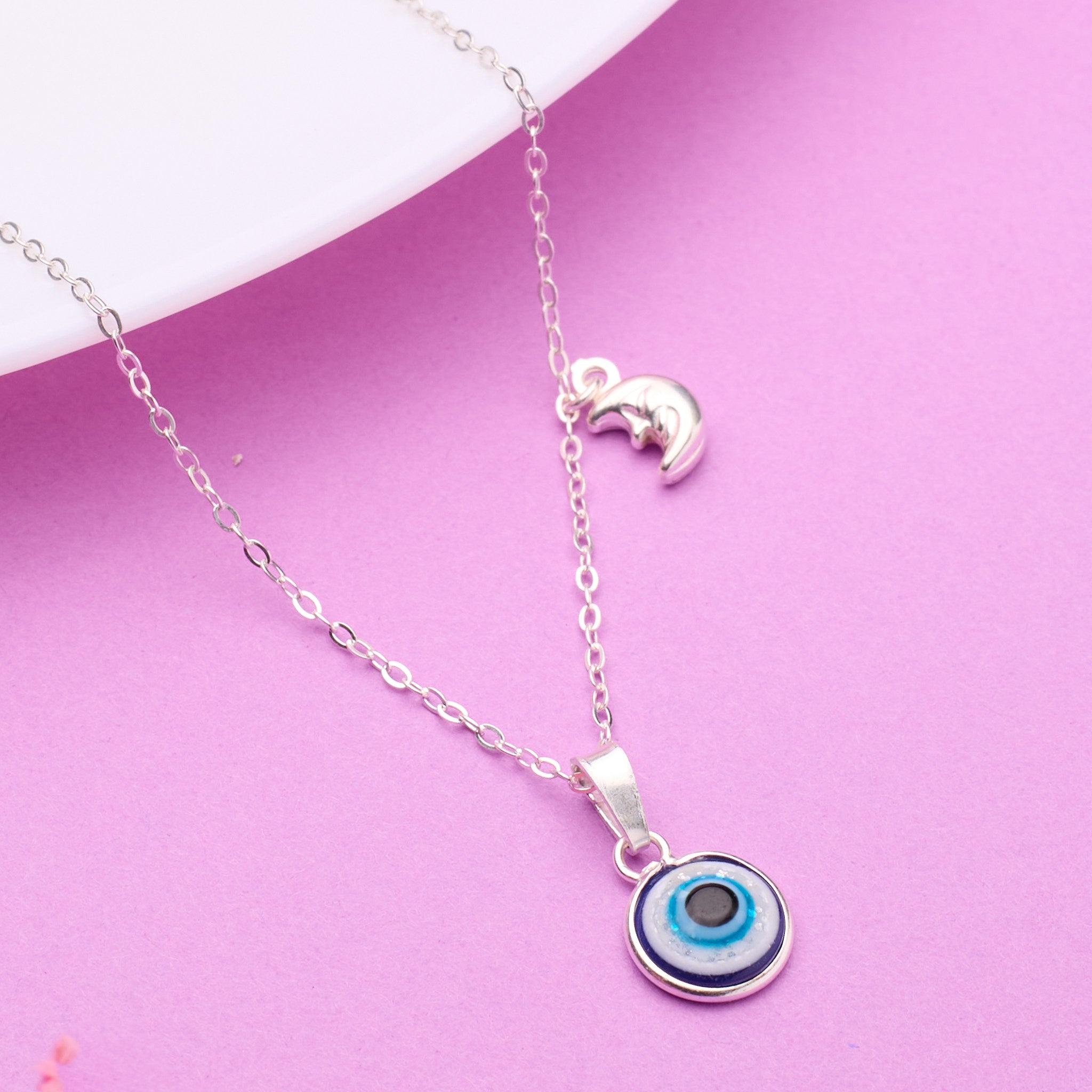 Silver necklace with a blue evil eye pendant on a pink background 925 Silver pendant for women