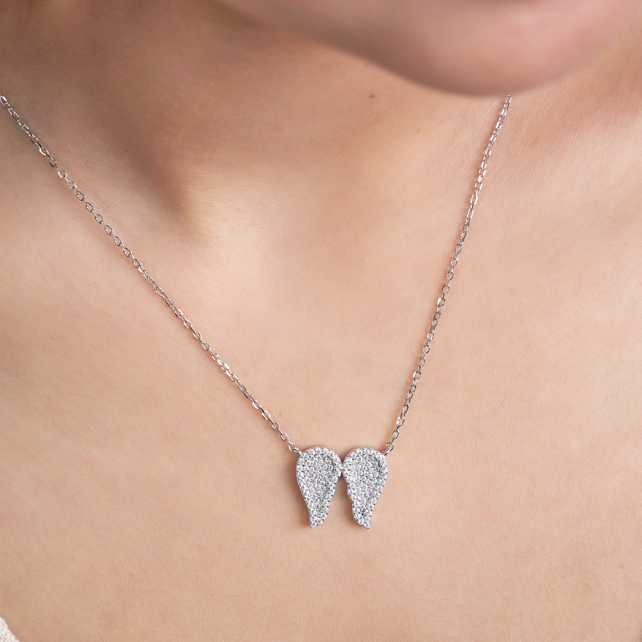 Pure Silver necklace with angel wing pendants on a person's neck