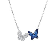 Butterfly-shaped necklace with one blue gem and one silver gem on a white background