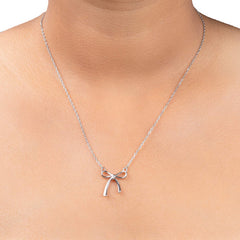 A delicate silver chain necklace with a small bow-shaped pendant, shown worn on a model's neck against a clean white background.